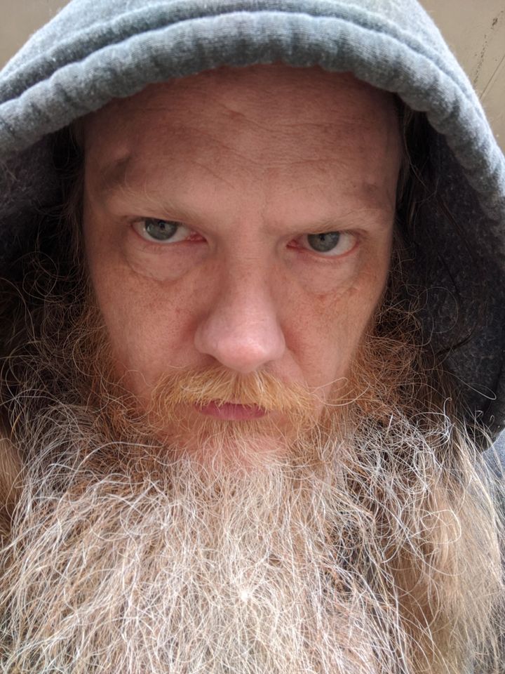 Press photo: Jim Moon of Taxxess in a grey hood, close portrait